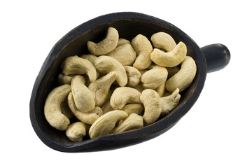 raw cashew nuts on a wooden scoop, isolated on white