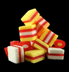 Stack of colorful striped fruit flavored candies on black.