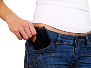 The female hand fills the pocket with a notebook of jeans