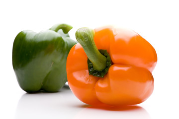 Zwei Paprika - ein oranger vorne, ein grüner hinten