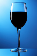 A glass of red wine on a reflective surface.