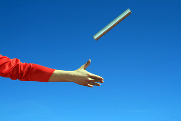 hands passing the batton against blue sky