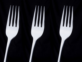 3 silver forks on a black background
