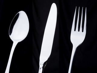 a silver spoon, knife, fork on a black background