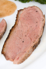 slices of a roasted duck fillet on a white plate