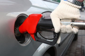 Bright red gas pump inserted into an automobile gasoline tank