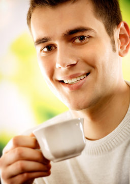 Portrait of young man with cup of tea or coffee
