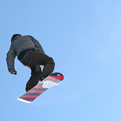 Fototapeta na wymiar Wysokiego latania snowboarder w powietrzu na tle błękitnego nieba