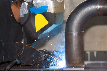 Welder working on metal tubes