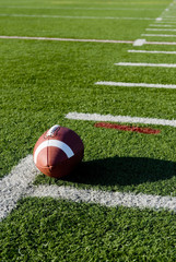 A brown leather American football on a green football field