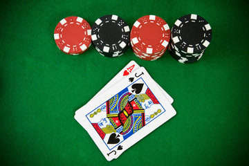 Ace of hearts and black jack with poker chips. Top view.
