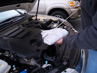 man checking oil level in car engine