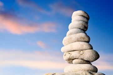 Stack of balanced pebbles, stones against colorful blue sky