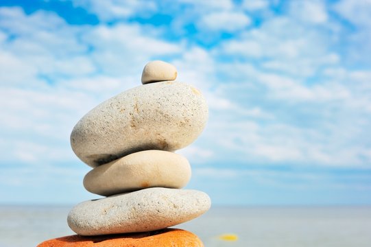 Stack of balanced pebbles, stones against colorful blue sky