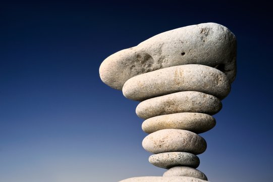 Stack of balanced pebbles, stones against colorful blue sky