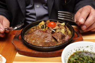 A man eats a steak dish in restaurant