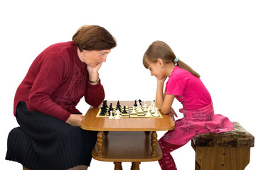 The grandmother and the granddaughter play a chess.