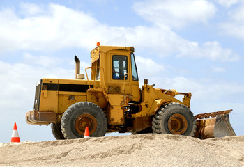 Yellow excavator at work against blue sky