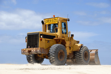 Obraz premium Yellow excavator at work against blue sky