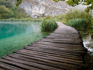 Turquoise water with fish and a wooden path in Plitvice.