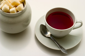 Cup of tea and sugar on grey background.