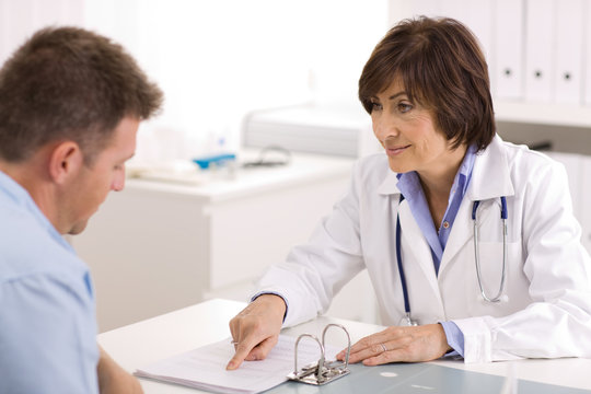 Smiling senior female doctor talking with male patient