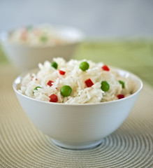 two bowls of  rice  with peas and peppers