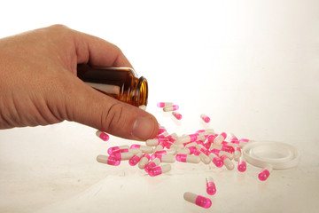 Hand holding a pill bottle with pill capsules spilling out