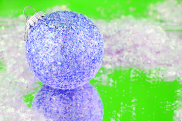 blue sparkly christmas ball with reflection on green