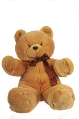 Big soft teddy bear with bow around the neck, isolated on white
