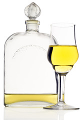 a liquor glass  and flask with yellow liquor on white