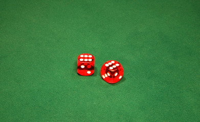 Two red dices on the green table in casino