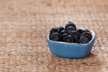 blueberries in a small blue dish on rustic background