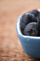 blueberries in a small blue dish on rustic background