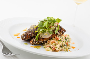 Gourmet salmon dish garnished with vegetables, white background.