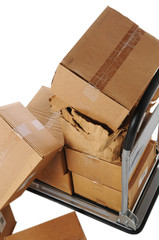 Stack of plain brown boxes falling off small cart