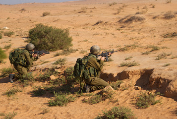 Men aiming with rifles in desert 
