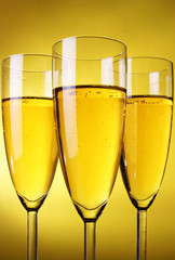 Three glasses of champagne over yellow background