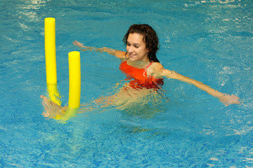 The young girl does exercise with aqua noodles