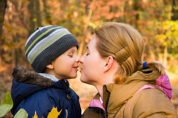 Mother kissing her 3 years old son in autumnal scenery