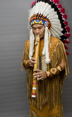 Portrait of a native american playing at a flute in a studio