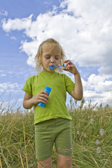 Children blowing bubbles on summer meadow