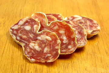 Slices of boloney on a wooden board.