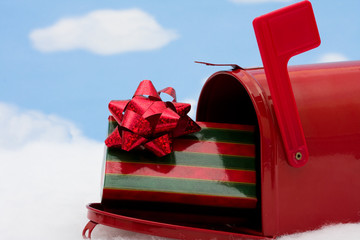 Red mailbox filled with presents and the flag up sitting on snow