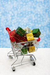 Shopping cart filled with presents on snow, Christmas shopping