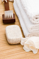 Fototapeta na wymiar bath accessories with soap brush and towel on bamboo