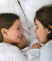 two young girls lying in the bed together