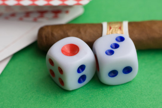 two dices with cigar and cards on green