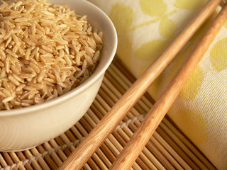 Raw rice and chopsticks on a bamboo carpet