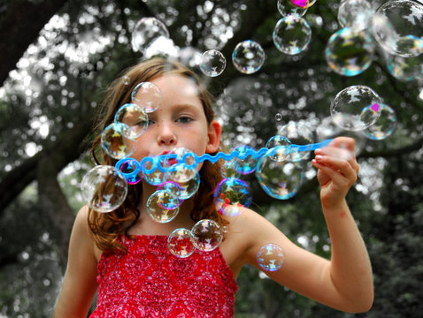 Young girl blowing lots of bubbles outside